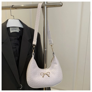 Detail of white crocodile texture hobo bag with a gold bow buckle and detachable strap