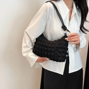 Minimalist black bubble textured shoulder bag with knot strap and metallic ring detail