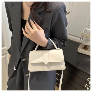 Detail of minimalist cream leather handbag with envelope flap and sleek top handle