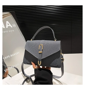 Detail of dark gray denim crossbody bag with a horseshoe buckle and sturdy top handle