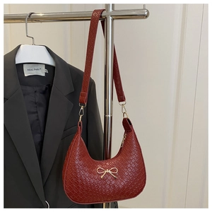 Detail of red crescent hobo bag with crocodile texture and gold bow metal buckle