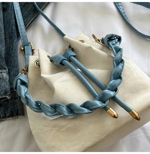 Close-up of contrast woven handle and drawstring detail on beige bucket bag