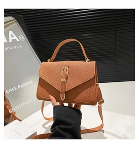 Detail of retro brown crossbody bag with fabric texture and gold buckle closure