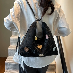 Black ruched tote bag with colorful heart patches shown on model in indoor setting