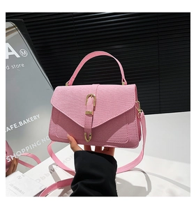 Detail of light pink crossbody bag with gold U-shaped hardware and fine crossgrain texture