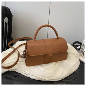 Detail of caramel brown leather handbag showing geometric stitching and silver metal hooks