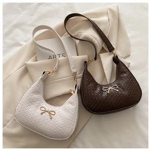 Detail of woven hobo bags in beige and brown with elegant golden bow metal accent