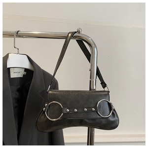 Détail d'un sac sous le bras en cuir mat noir avec anneaux métalliques et clous argentés sur rack