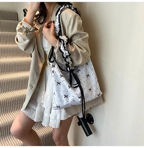 Floral canvas tote bag with ruffled shoulder strap and black bow patterns on white fabric