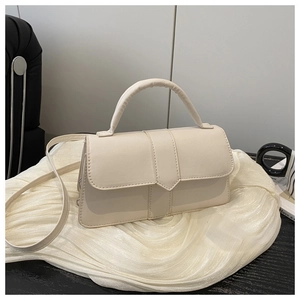 Detail of cream structured handbag with cylindrical handle and V-shaped flap closure