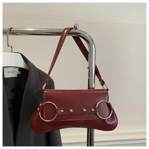 Détail du sac bandoulière bordeaux en similicuir avec anneaux argentés et rivets