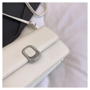 Detail of white matte leather handbag showing the silver oval buckle and metal strap buckle