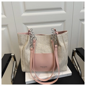 Close-up of cream woven straw tote bag featuring a pink leather pocket and chain strap