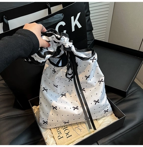 Detail of white drawstring dust bag with black polka dots and small bow prints