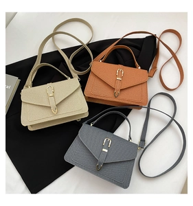 Close-up of three retro flap crossbody bags in beige, caramel brown and charcoal gray