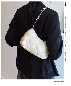 Close-up of white quilted leather bag with silver chain strap worn on shoulder