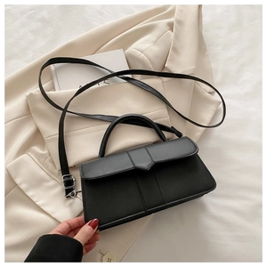 Detailed view of black matte leather bag with adjustable silver buckle and top handle