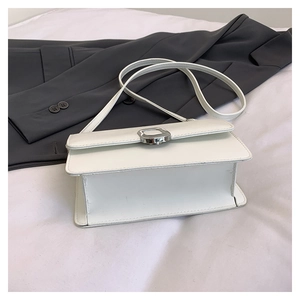 Detail view of white leather crossbody bag featuring a silver rectangular twist lock closure