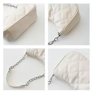 Detail view of cream quilted shoulder bag showing stitching, chain strap and zipper