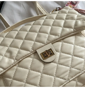 Close-up of beige quilted tote bag featuring a gold rectangular twist-lock closure