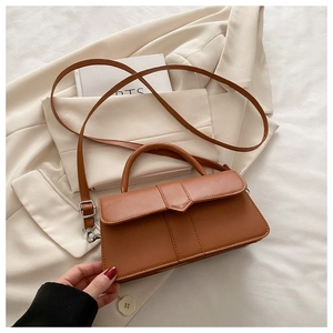 Detail of caramel brown PU leather crossbody bag with V-shaped flap and silver hardware