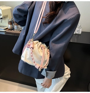 Detail of cream drawstring bucket bag with pink woven handle and a cute cartoon charm