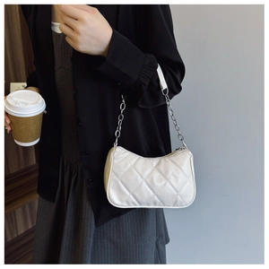 Detail of white quilted underarm bag with diamond stitching and metal chain strap