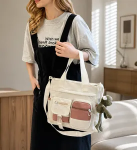 Dettaglio borsa tote in tela crema con tasche multiple e ciondolo a forma di rana