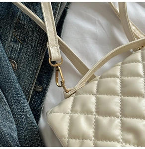 Close-up of quilted cream leather bag with golden hardware and stitching details