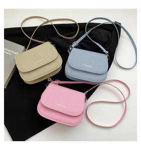 Detailed view of beige, blue, and pink crossbody bags with textured twill surface