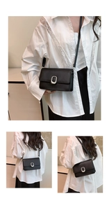 Close-up of minimalist black matte leather crossbody bag with silver oval metal buckle