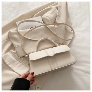 Detail of cream rectangle handbag with vertical stitching on beige blazer background