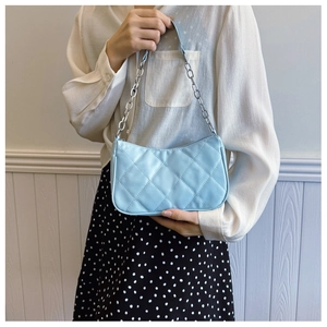 Detail of light blue quilted shoulder bag with diamond stitching and silver chain strap