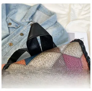 Detail view of colorful patchwork leather handbag with embossed textures and sturdy handle