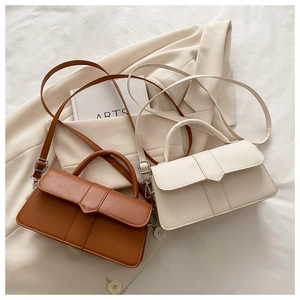 Detail view of brown and beige square crossbody bags on white fabric lifestyle setting