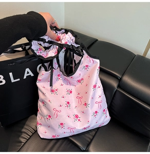 Detail of pink floral satin tote bag featuring rose patterns and black ruffle drawstring