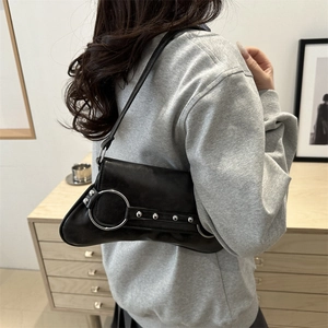 Sac à bandoulière vintage en cuir noir avec anneaux argentés et clous sur un modèle