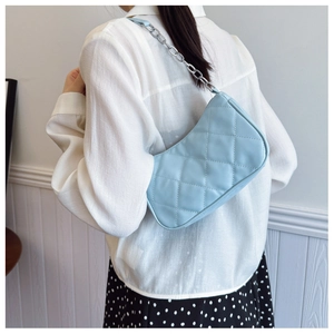 Close-up of quilted light blue shoulder bag with silver chain strap on model