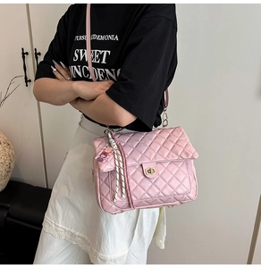 Detailed shot of pink quilted shoulder bag with gold twist lock and woven tassel