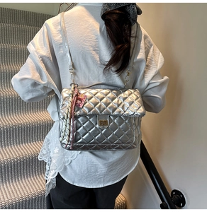 Detailed view of silver quilted tote bag with metallic finish and scarf keychain decoration