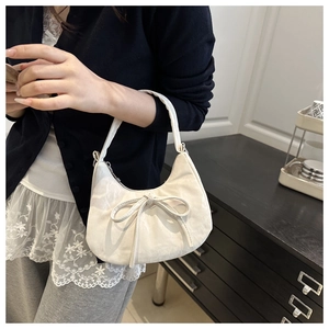 Detail of a creamy white bow crescent bag with soft leather texture and chic design