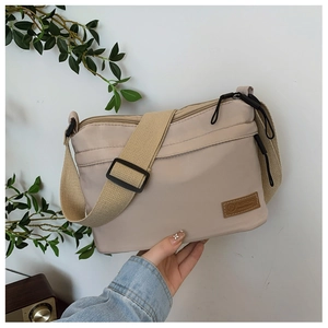 Detail of beige nylon crossbody bag showing multi-zip layers and fashion outdoor label