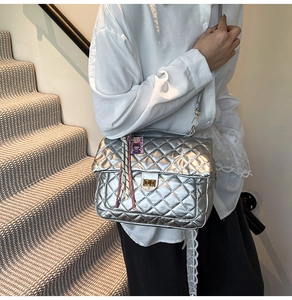 Detail of silver quilted tote bag featuring metallic texture and golden swivel lock