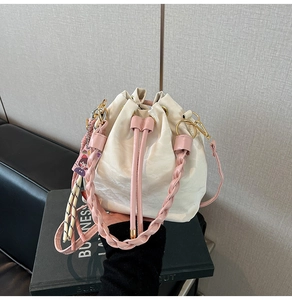 Detail of cream bucket bag with pink woven handle and cute cartoon charm accessory