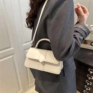 Cream vintage crossbody bag with flap and handle shown on a model in casual office attire