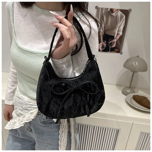 Detailed view of black hobo bag with a large bow and textured velvet finish
