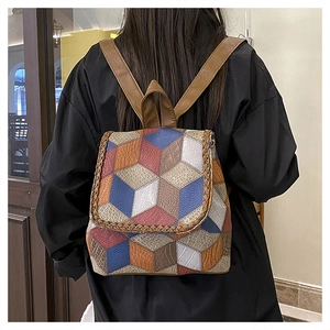 Detail view of colorful geometric patchwork backpack with woven trim and brown straps