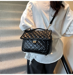 Classic black quilted shoulder bag with gold twist lock shown on model at a side view