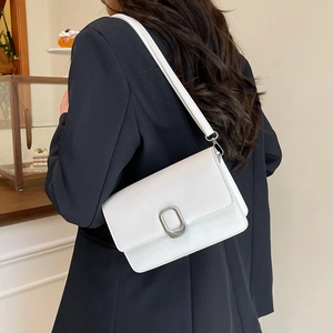 Minimalist white leather crossbody bag with silver oval metal buckle on a model