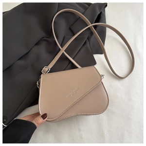 Detail of beige PU leather bag with asymmetric flap and fashion trend logo engraving